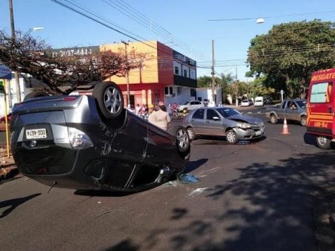 Colisão em cruzamento de avenida em obras deixa carro de rodas para cima